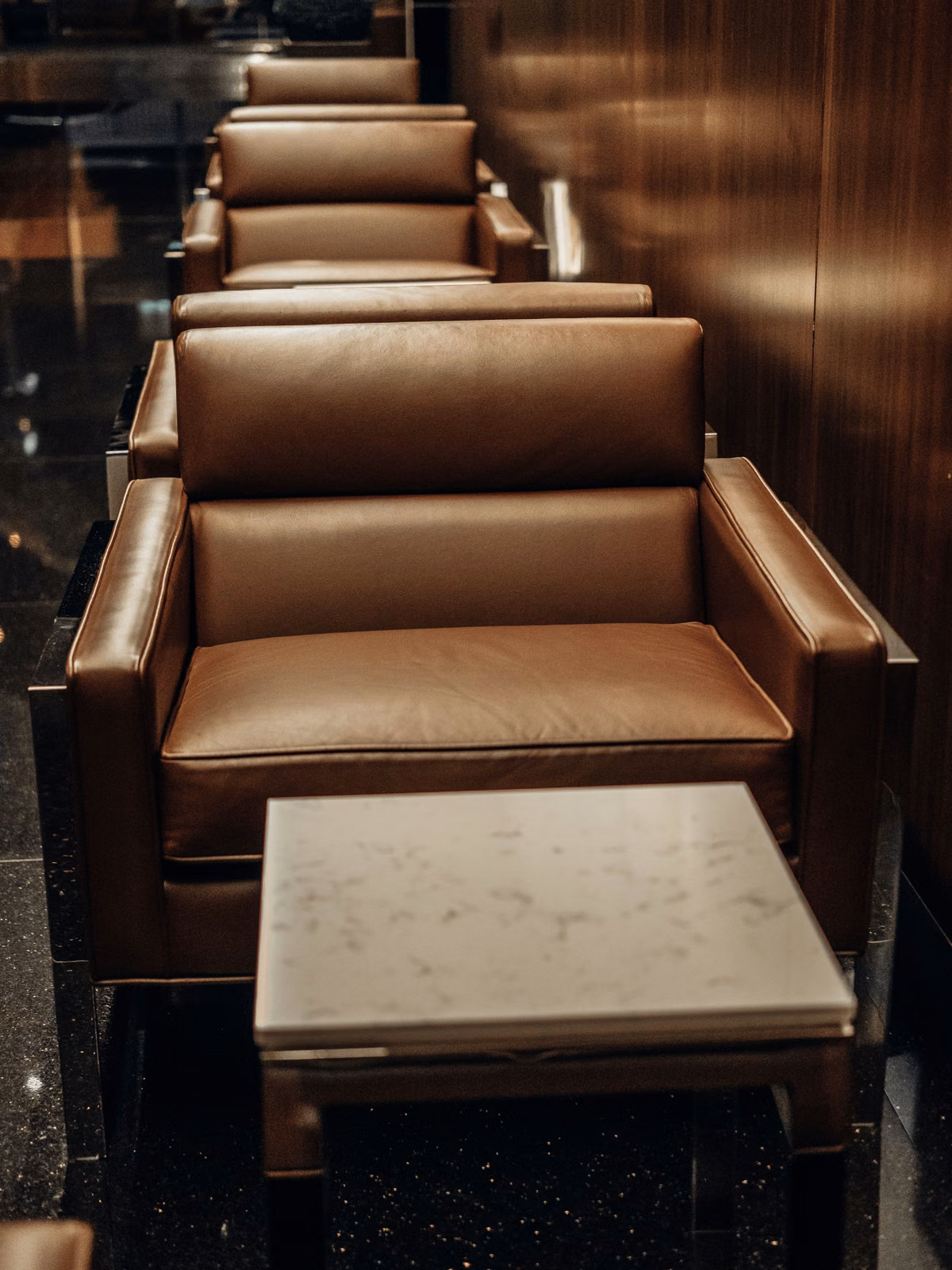 Licensed stock: cognac leather lounge chairs along wood paneling — illustrative private-club calm, not a named club.